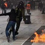 Διαδηλωτής κυνηγάει άνδρα των ΜΑΤ μέσα στις φλόγες και τον χτυπάει με το κράνος – Δείτε το βίντεο